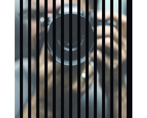 Akustikpaneel digital bedruckt Shoot 1 572,5 x 572,5 x 19 mm Eine Person hinter Gittern mit einer Kamera.