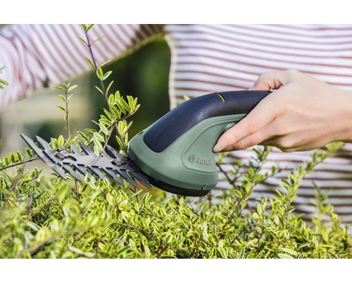 Eine Person schneidet mit einer akkubetriebenen Strauchschere eine Hecke. Bosch Logo.