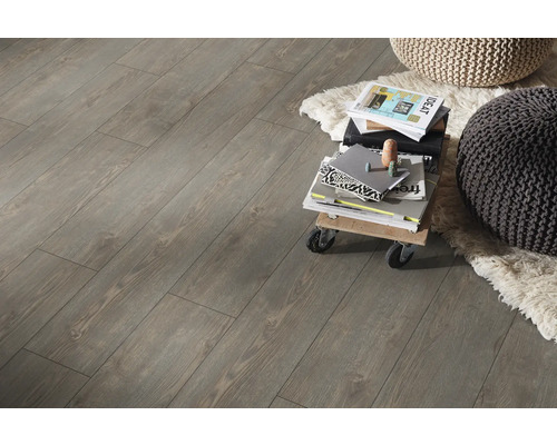 Innenaufnahme von Laminatboden mit Holzoptik, mit einem kleinen Rollwagen, Büchern und zwei Sitzkissen