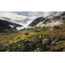 Landschaft mit Bergen, Wolken und Hütten mit Grasdächern