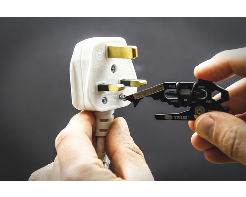 Ein Mehrzweckwerkzeug wird verwendet, um eine Schraube an einem Stecker zu lösen.