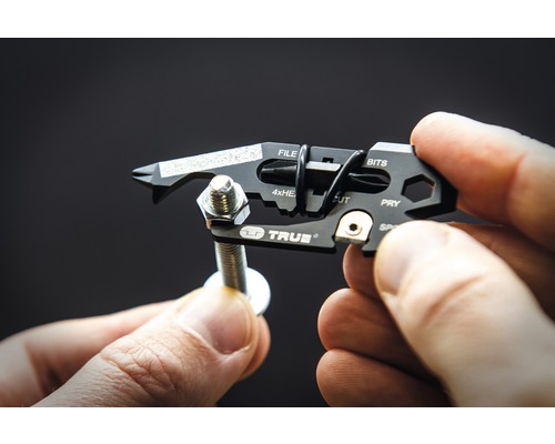 Multitool in Verwendung mit Schraube und Mutter in der Hand