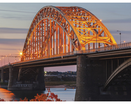 Ansicht einer beleuchteten Bogenbrücke bei Dämmerung.