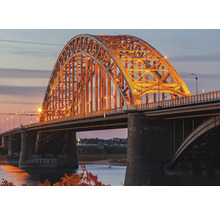 Ansicht einer beleuchteten Bogenbrücke bei Dämmerung.