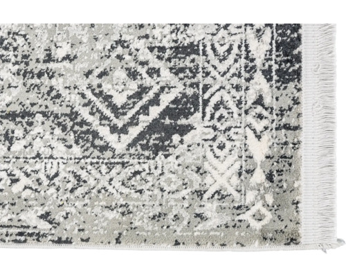 Detailansicht eines grauen Teppichs mit abstraktem Muster und Fransen