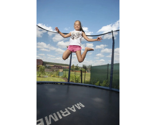 Mädchen springt auf einem Gartentrampolin mit Sicherheitsnetz