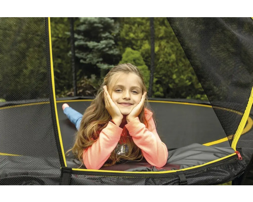 Mädchen entspannt auf einem Gartentrampolin mit Sicherheitsnetz