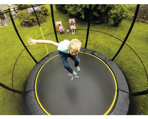 Junge springt auf einem runden Gartentrampolin mit Sicherheitsnetz