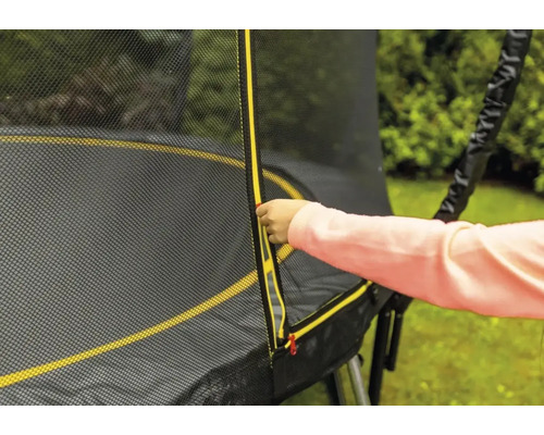 Ein Kind öffnet den Reißverschluss des Sicherheitsnetzes eines Gartentrampolins.