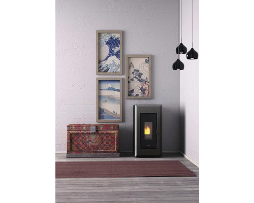 Wohnraum mit Pelletkaminofen, Truhe, Teppich, Hängelampen und gerahmten Bildern an der Wand