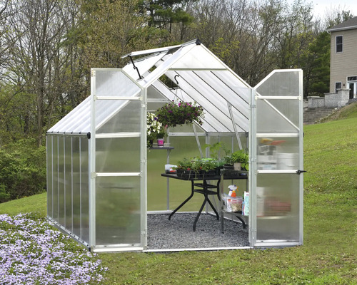 Gewächshaus mit Pflanzen auf einem Tisch im Garten.