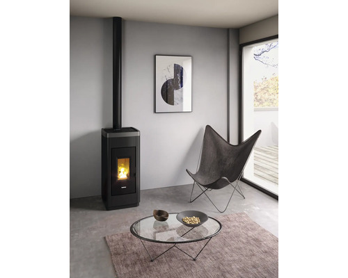 Wohnzimmer mit Pelletofen, Sessel und Couchtisch auf Teppich
