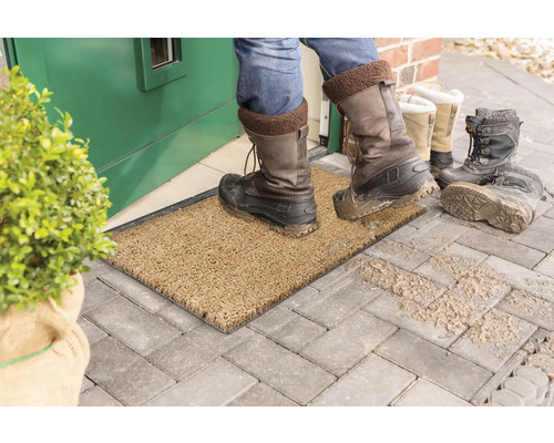 Fußabtreter vor einer Haustür mit schmutzigen Stiefeln