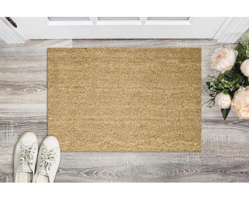 Fußmatte vor einer Tür mit Schuhen und Blumenarrangement