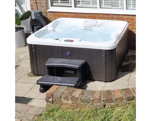 Quadratischer Whirlpool mit Treppe im Garten.