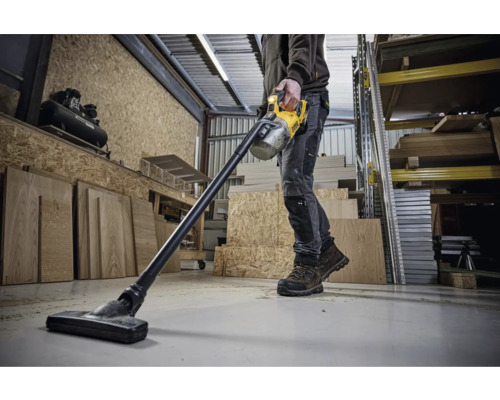 Mann benutzt einen Akku-Staubsauger von DeWalt in einer Werkstatt.