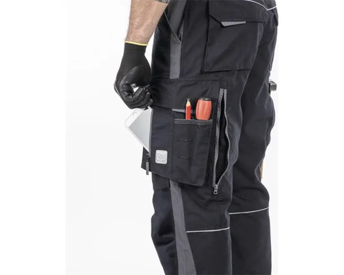 Detailaufnahme einer Arbeitshose mit mehreren Taschen, in denen sich ein Stift, ein Spitzer und ein Tablet befinden.