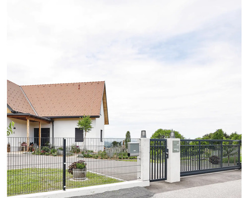 Einfamilienhaus mit Schiebetor und Zaun zur Grundstücksbegrenzung.