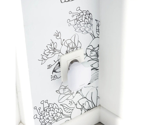 Elektrisches Gerät in Steckdose vor floraler Wand
