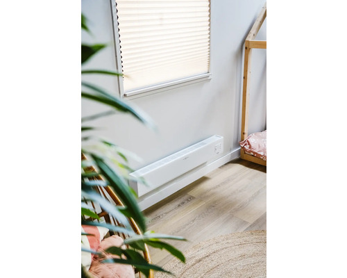 Szene mit einem weißen Wandkonvektorheizgerät in einem Raum mit einem Holzhausbett