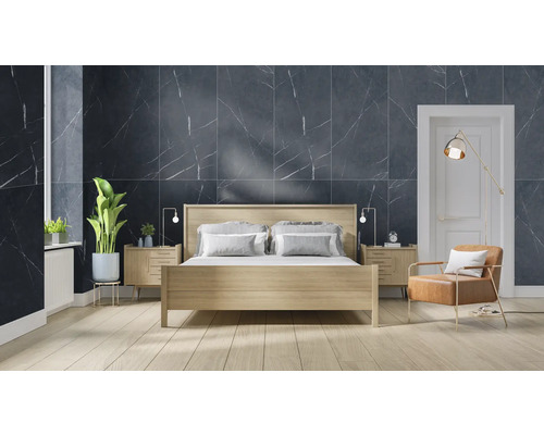 Schlafzimmer mit Bett, Nachttischen, Sessel und Wandfliesen in Marmoroptik