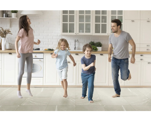 Familie tanzt in einer hellen Küche mit Fliesenboden.
