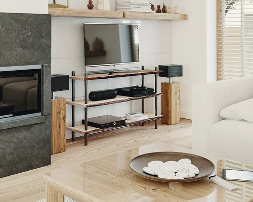 Wohnzimmer mit Fernsehgerät auf Holzregal, Lautsprechern und Couchtisch