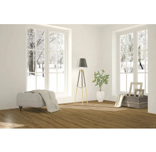 Heller Raum mit Fensterblick auf eine verschneite Winterlandschaft, ausgestattet mit Hocker, Stehlampe und Pflanze.