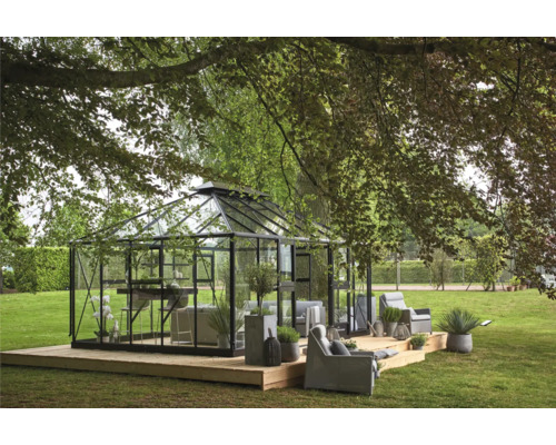Gewächshaus mit Sitzgelegenheiten auf einer Holzterrasse in einem Garten.