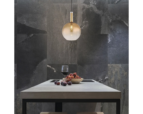 Szene mit einer Pendelleuchte über einem Esstisch mit einem Glas Wein und Obst