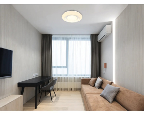 Wohnzimmer mit Deckenleuchte, Sofa, Schreibtisch und Vorhängen