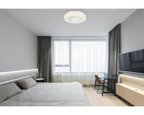 Schlafzimmer mit Doppelbett, Schreibtisch und runder Deckenleuchte
