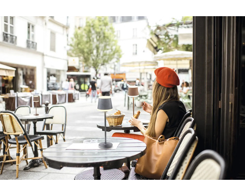 Szene eines Straßencafés mit Tischen und Tischlampen.