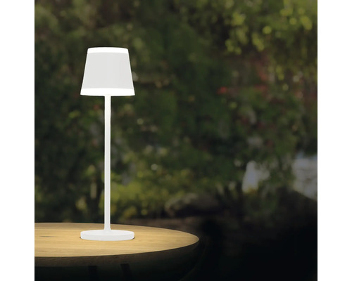 Weiße Tischleuchte auf einem Tisch im Garten.