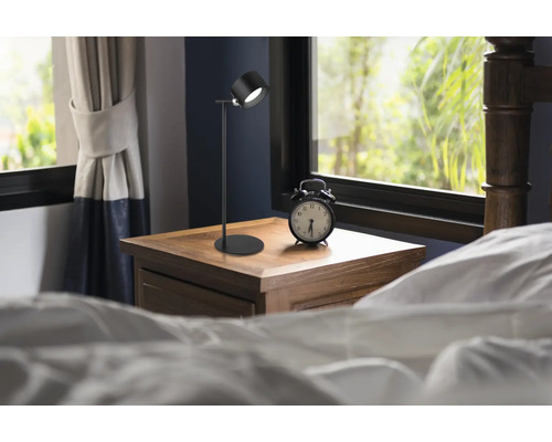 Schlafzimmer mit Nachttischlampe und Wecker auf einem Nachttisch