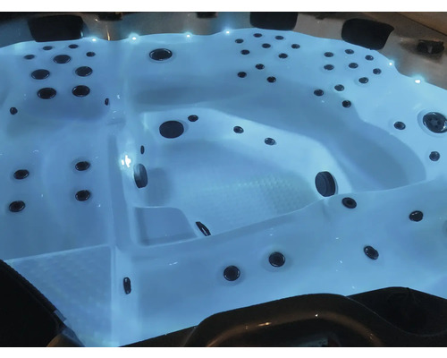 Blick auf einen beleuchteten Whirlpool mit Düsen.