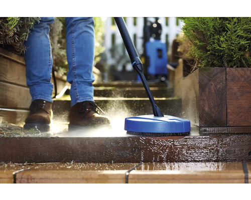 Person reinigt Terrasse mit Flächenreiniger und Hochdruckreiniger