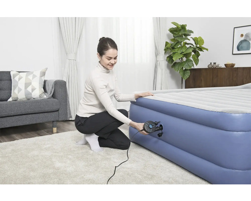 Frau pumpt Luftmatratze mit einer Luftpumpe auf.