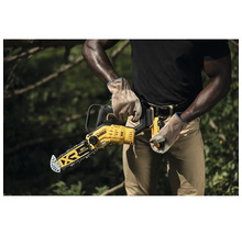Eine Person hält eine gelbe DeWalt Akku-Kettensäge in der Hand
