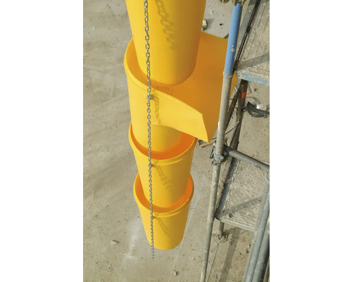 Gelbe Bauschuttrutsche mit Kette und Gerüst im Hintergrund