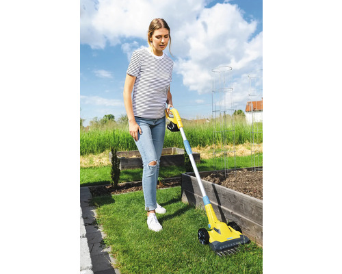 Eine Frau benutzt einen Vertikutierer im Garten.