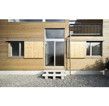 Fassade eines Hauses mit Holzverkleidung, Fenstern und einer Außentreppe