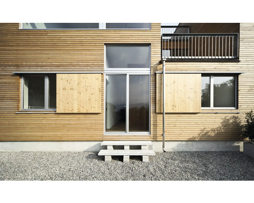 Fassade eines Hauses mit Holzverkleidung, Fenstern und einer Außentreppe
