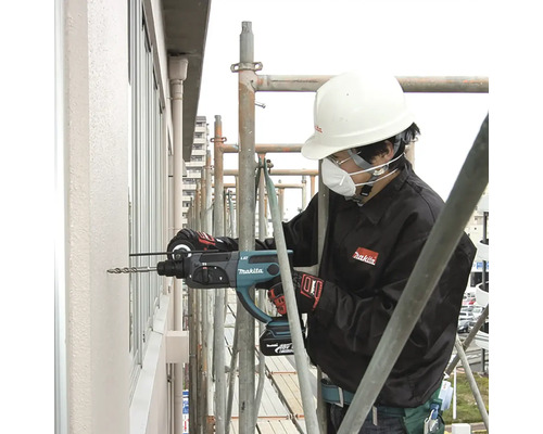 Ein Bauarbeiter bohrt mit einem Makita Bohrhammer ein Loch in eine Wand.