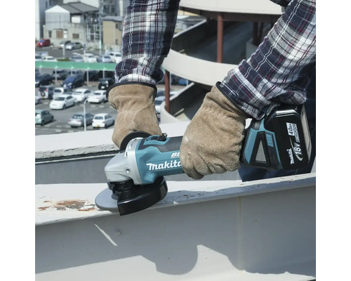 Handwerker in Schutzhandschuhen verwendet einen Akku-Winkelschleifer von Makita zum Schleifen von Metall.