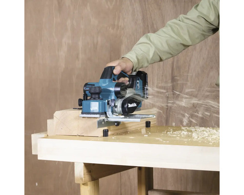 Aufsicht einer Person, die einen Hobel zum Glätten eines Holzstücks auf einer Werkbank verwendet