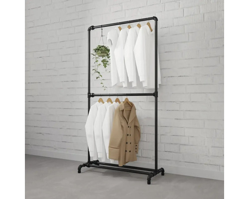 Schwarze Kleiderstange aus Metallrohr mit Kleidung und Pflanze