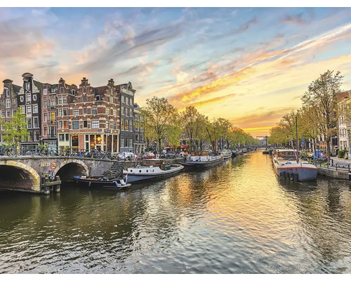 Kanalansicht in Amsterdam mit Hausbooten und Brücke bei Sonnenuntergang