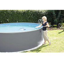 Frau reinigt einen runden Aufstellpool mit einem Kescher im Garten.