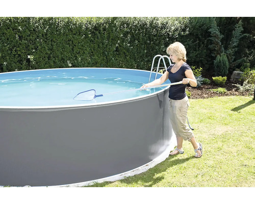 Frau reinigt einen runden Aufstellpool mit einem Kescher im Garten.
